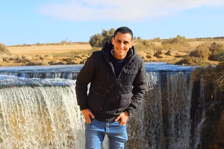 Visitor smiling at the scenic waterfall in Fayoum Oasis during a full day Jeep tour from Cairo or Giza.