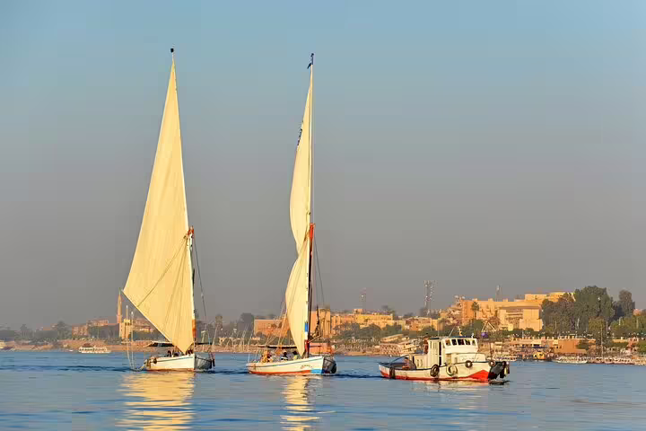 Felucca sailboats cruising the Nile in Luxor, scenic East and West Bank tour view near temples at sunset