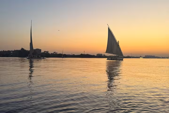 Two feluccas gliding on the Nile River at sunset, peaceful Cairo felucca tour with pickup included