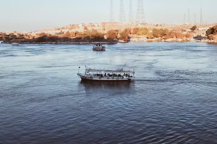 Nile River cruise in Aswan, Egypt with boat gliding on calm waters, scenic riverbanks on felucca tour