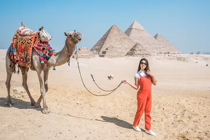 Traveler with decorated camel facing Giza Pyramids, Cairo tour with expert female Egyptologist and photo stops