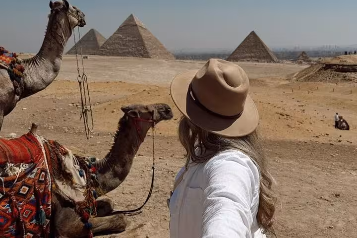 Traveler with camels facing Giza Pyramids on private female Egyptologist tour to pyramids and Great Sphinx
