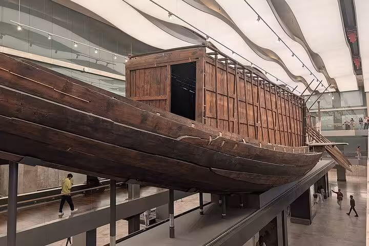 Ancient Egyptian wooden solar boat exhibit inside Grand Egyptian Museum on expert female Egyptologist tour