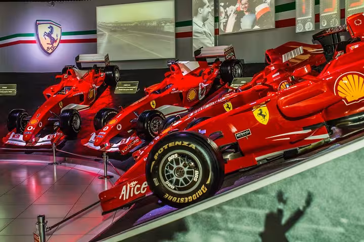 Row of iconic red Ferrari race cars displayed at the Ferrari Museum, a highlight of the Maranello tour from Florence.