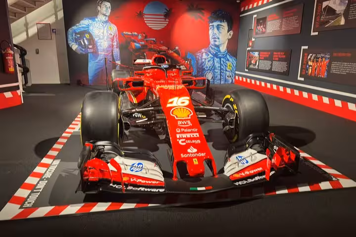 Explore the Ferrari museum featuring an iconic red F1 car with vibrant murals of legendary drivers on display.