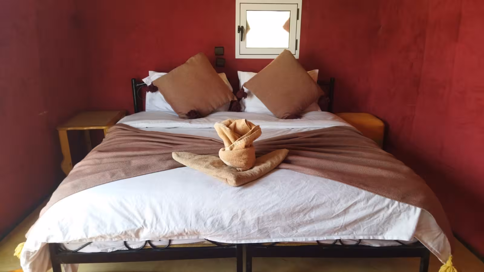 Cozy desert accommodation in Fes to Errachdia tour with plush bedding and vibrant decor.