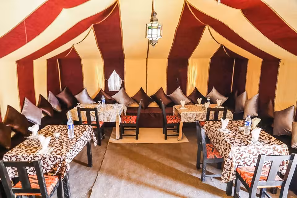 Luxurious desert tent dining setup with patterned tablecloths and traditional decor on the Fes to Marrakech tour.