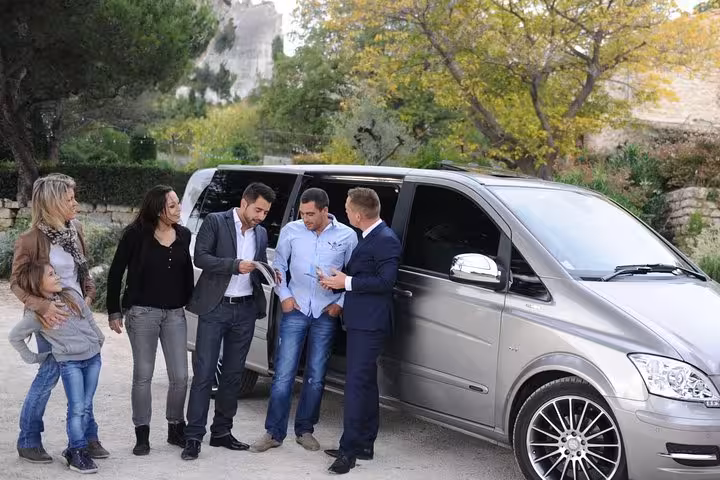 Group discussing travel plans beside a luxury van for Fes to Merzouga desert transfer.
