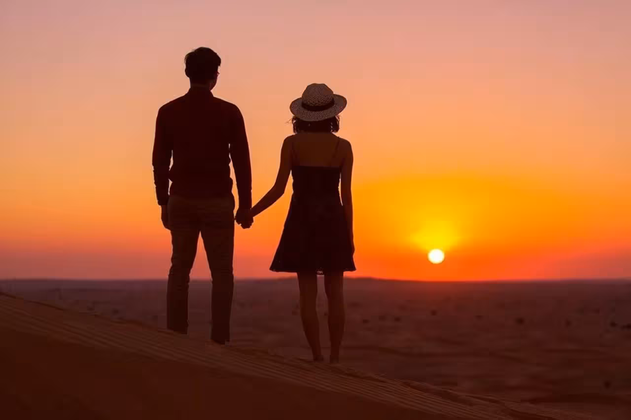 Romantic sunset view of a couple on a desert dune during 4-day Merzouga Sahara tour from Fes.
