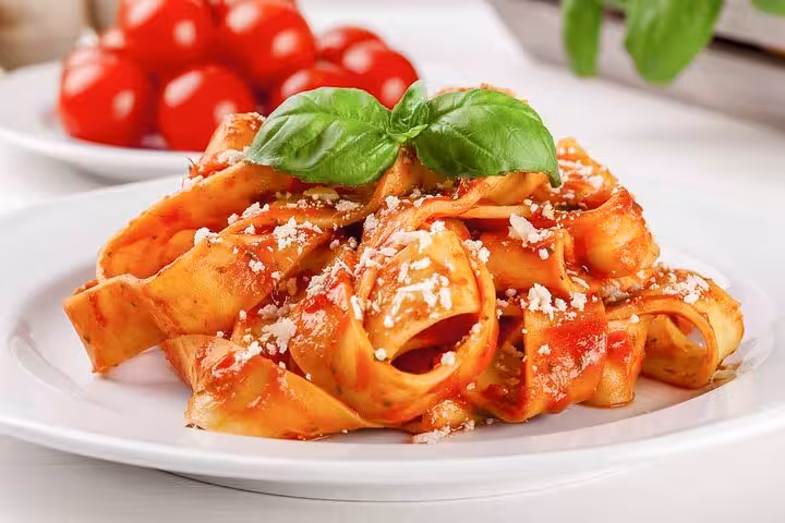 Freshly made fettuccine with tomato sauce and basil, highlighting a pasta cooking class in Piazza Navona, Rome.