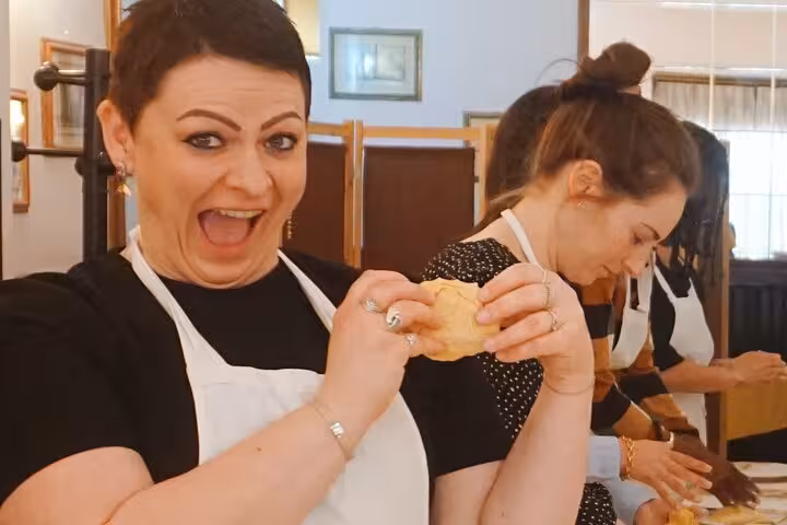 Excited participant crafting dough during Fettuccine pasta class in Rome, capturing the joy of Italian cooking.