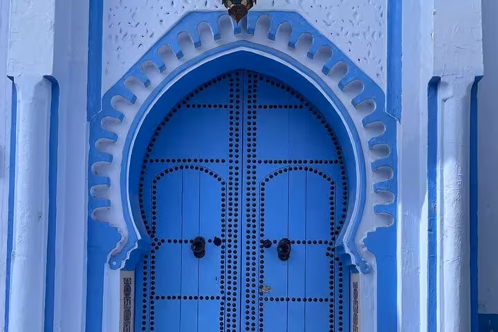 Stunning blue arched door in Chefchaouen, Morocco, highlighting Moorish architecture on a Fez to Chefchaouen tour.