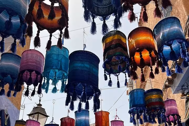 Colorful Moroccan lanterns hang vibrantly above a street in Chefchaouen, perfect for a guided tour from Fez.