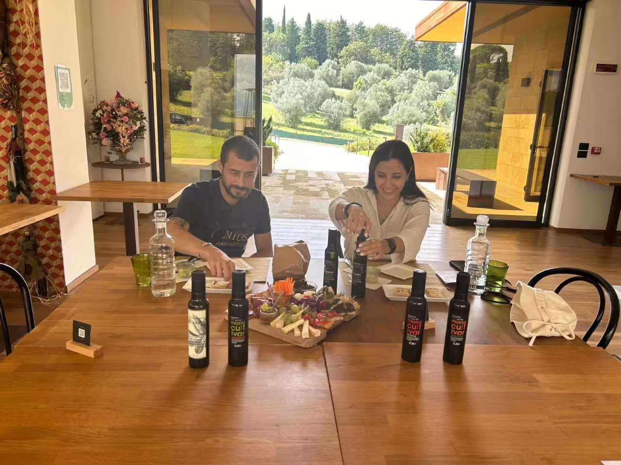 Guests tasting extra virgin olive oil at Frantoio Buonamici in Fiesole, with olive groves view and local snacks