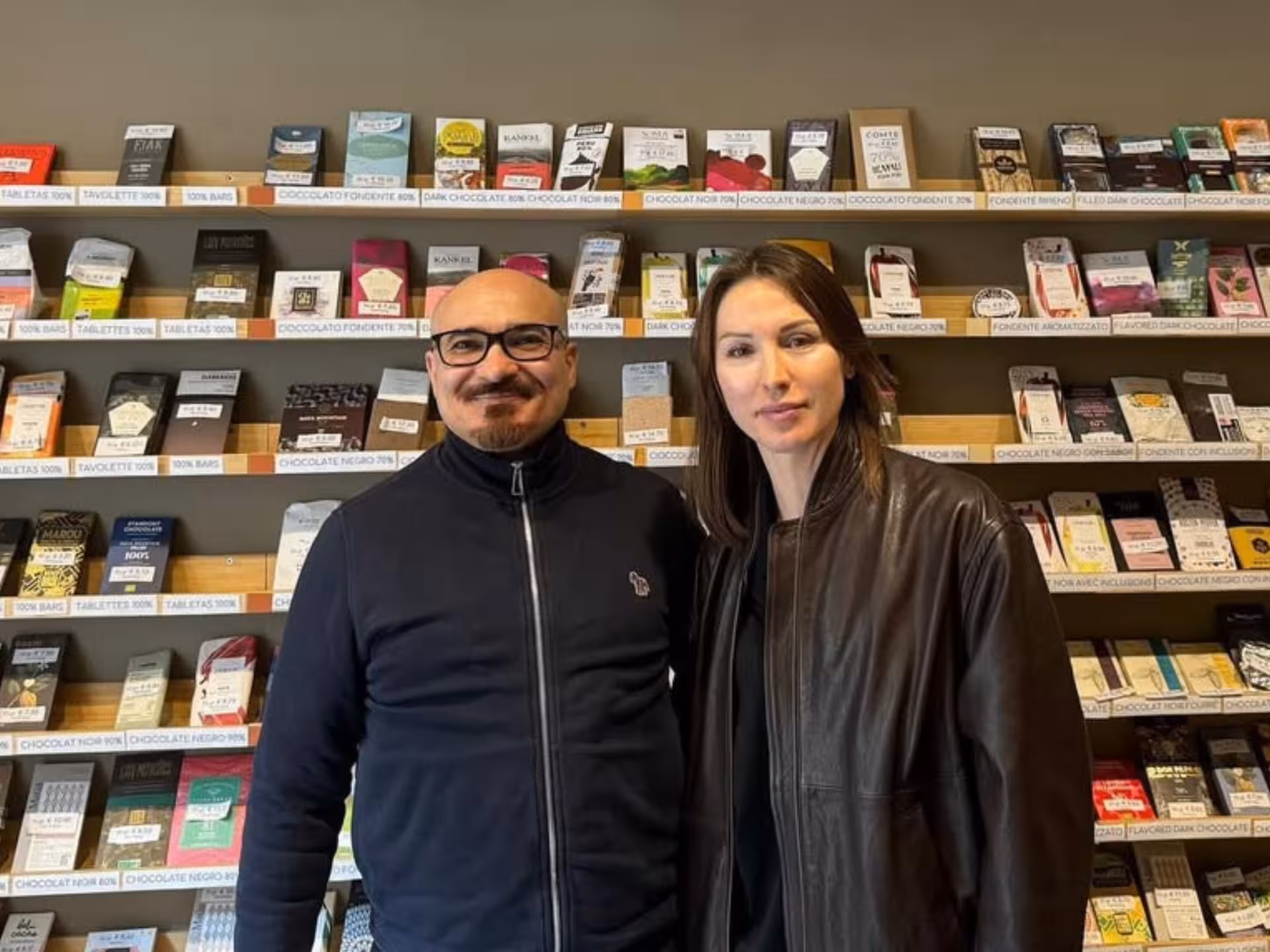 Two people standing in front of a display of diverse chocolate bars during a fine chocolate tasting in Turin.