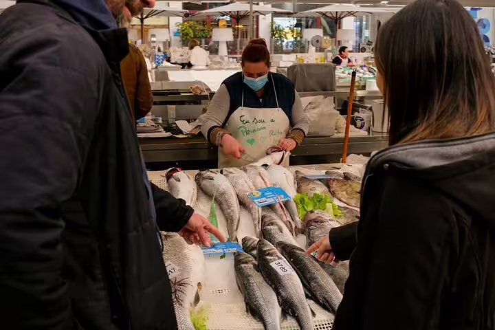 Visitors explore fresh seafood selections during a sea-to-table fish market tasting tour, guided by a knowledgeable vendor.