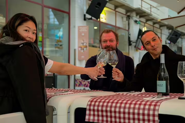 Group enjoying wine tasting at a seafood market tour, featuring fresh fish and local cuisine on a sea-to-table experience.
