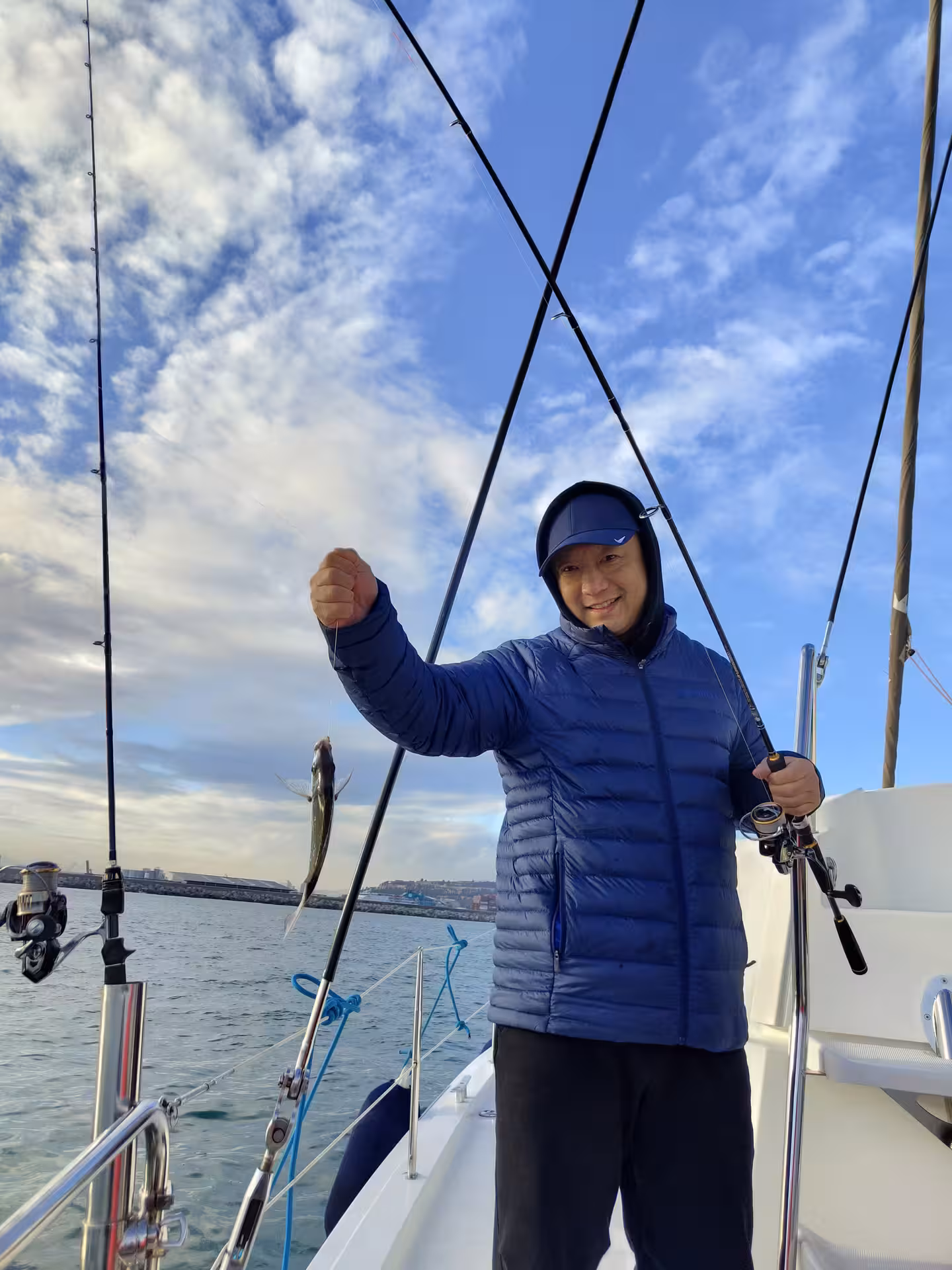 Fisherman on a Mediterranean boat holding a fresh catch, deep sea fishing charter experience with rods and reels