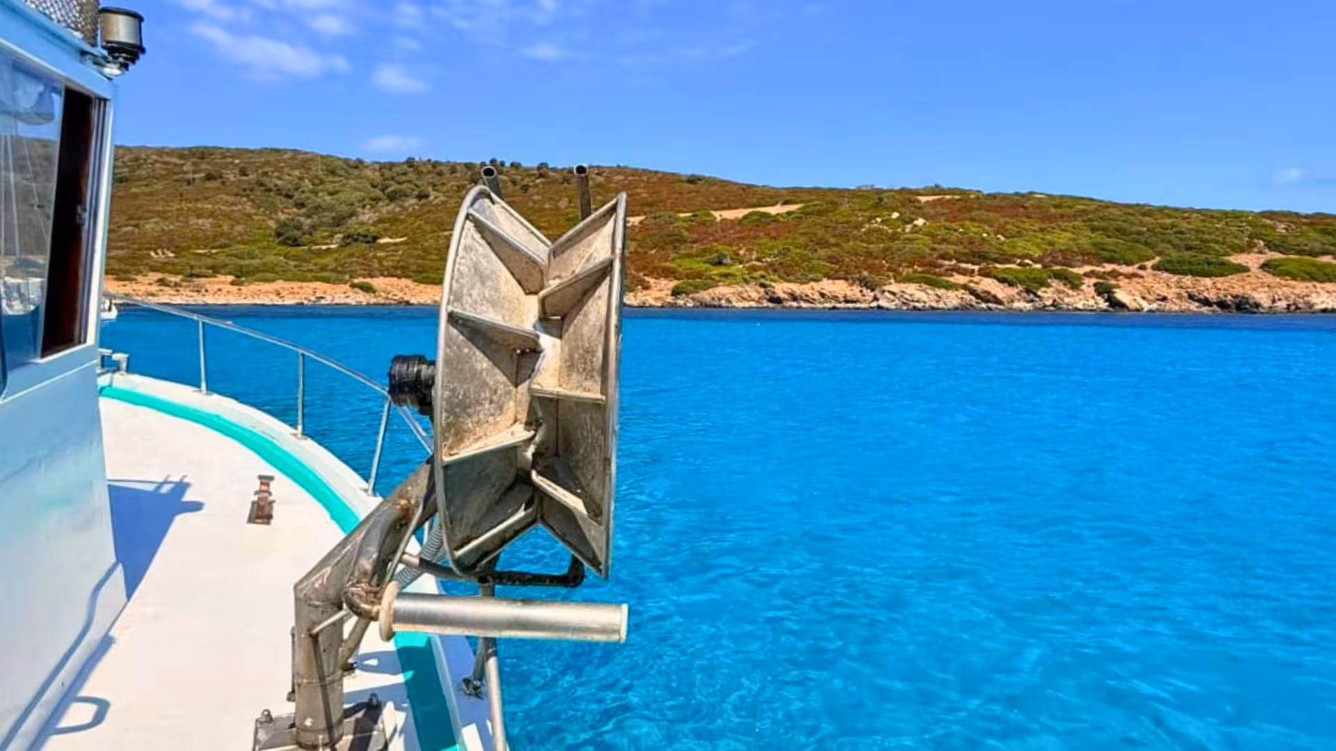 View from a fishing boat in Asinara Park, showcasing the clear blue waters and scenic coastline under a sunny sky.