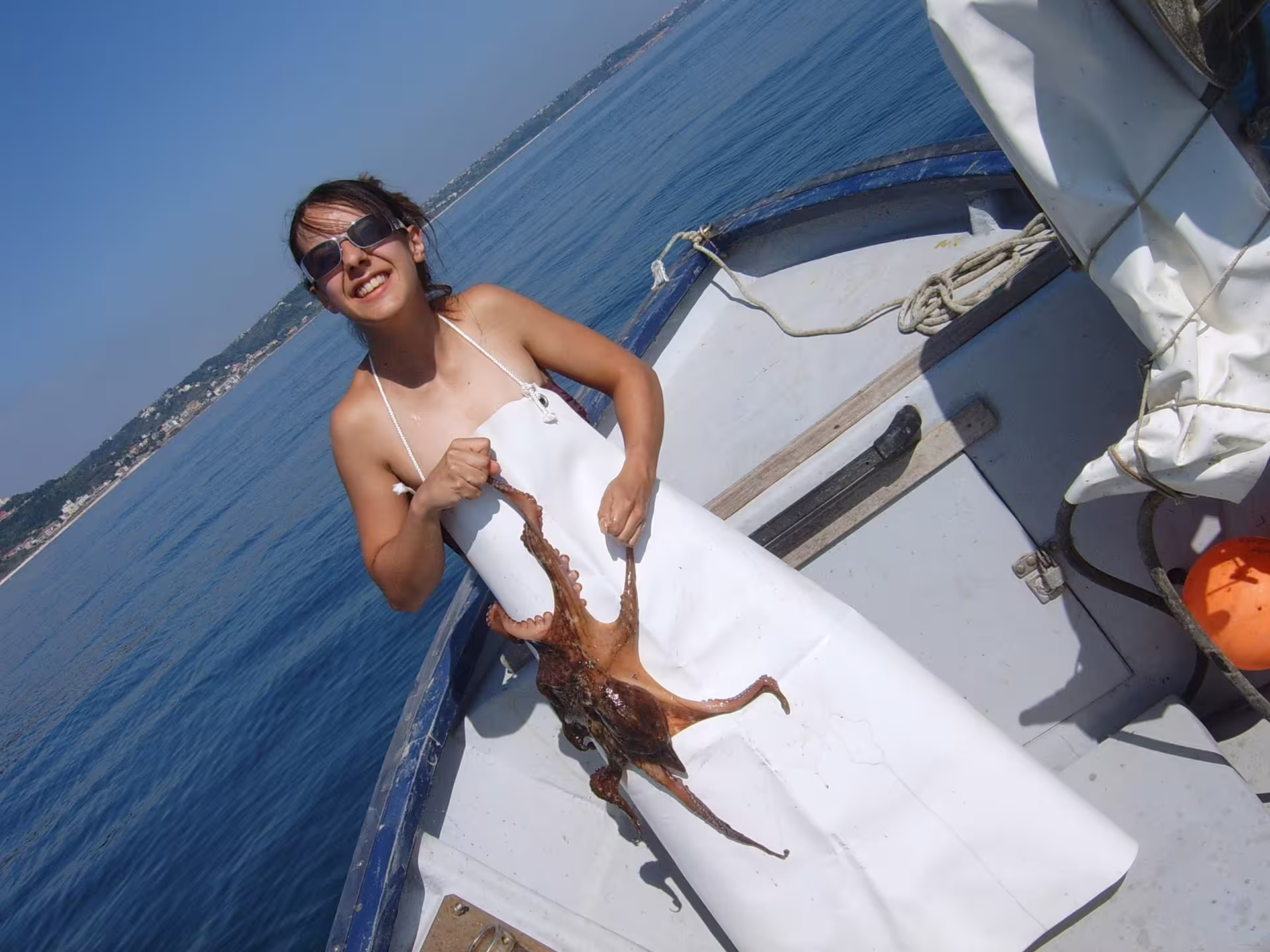 Guest on a boat holds a freshly caught octopus during Trabocchi Coast fishing tourism experience in Abruzzo