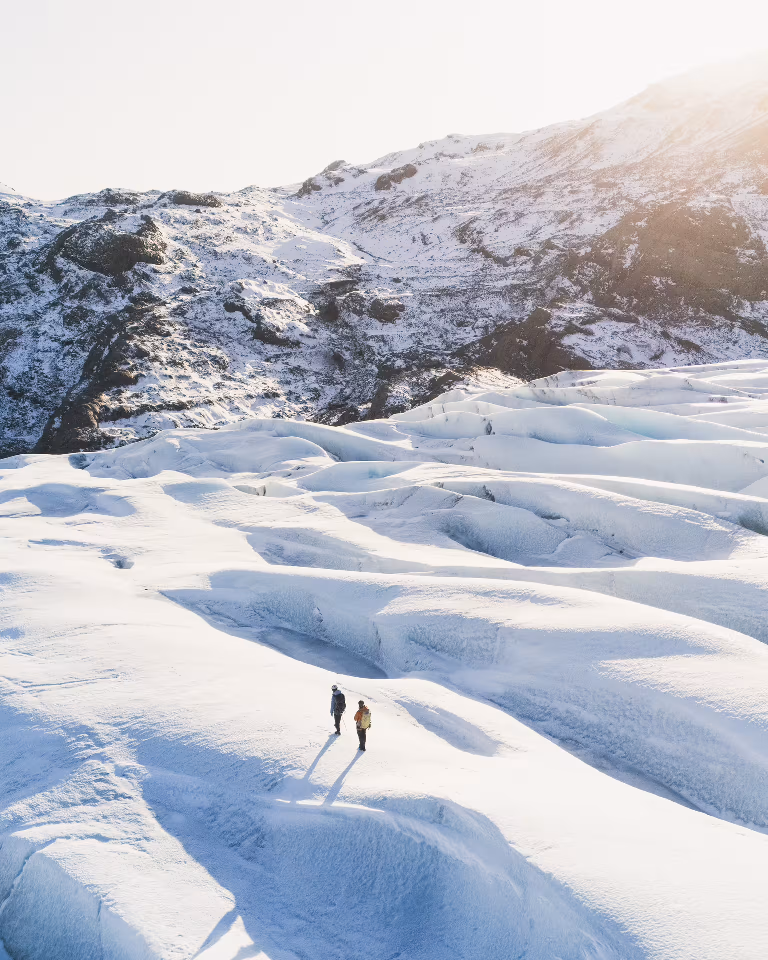 Hikers crossing sunlit Fláajökull glacier on a full-day kayak and glacier hike combo tour in Iceland