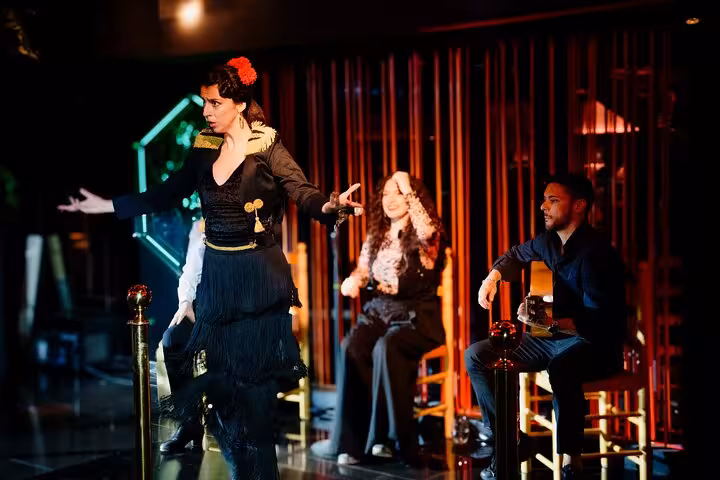 Flamenco dancer passionately performing with musicians on stage, highlighting cultural vibrancy in Barcelona's live show.