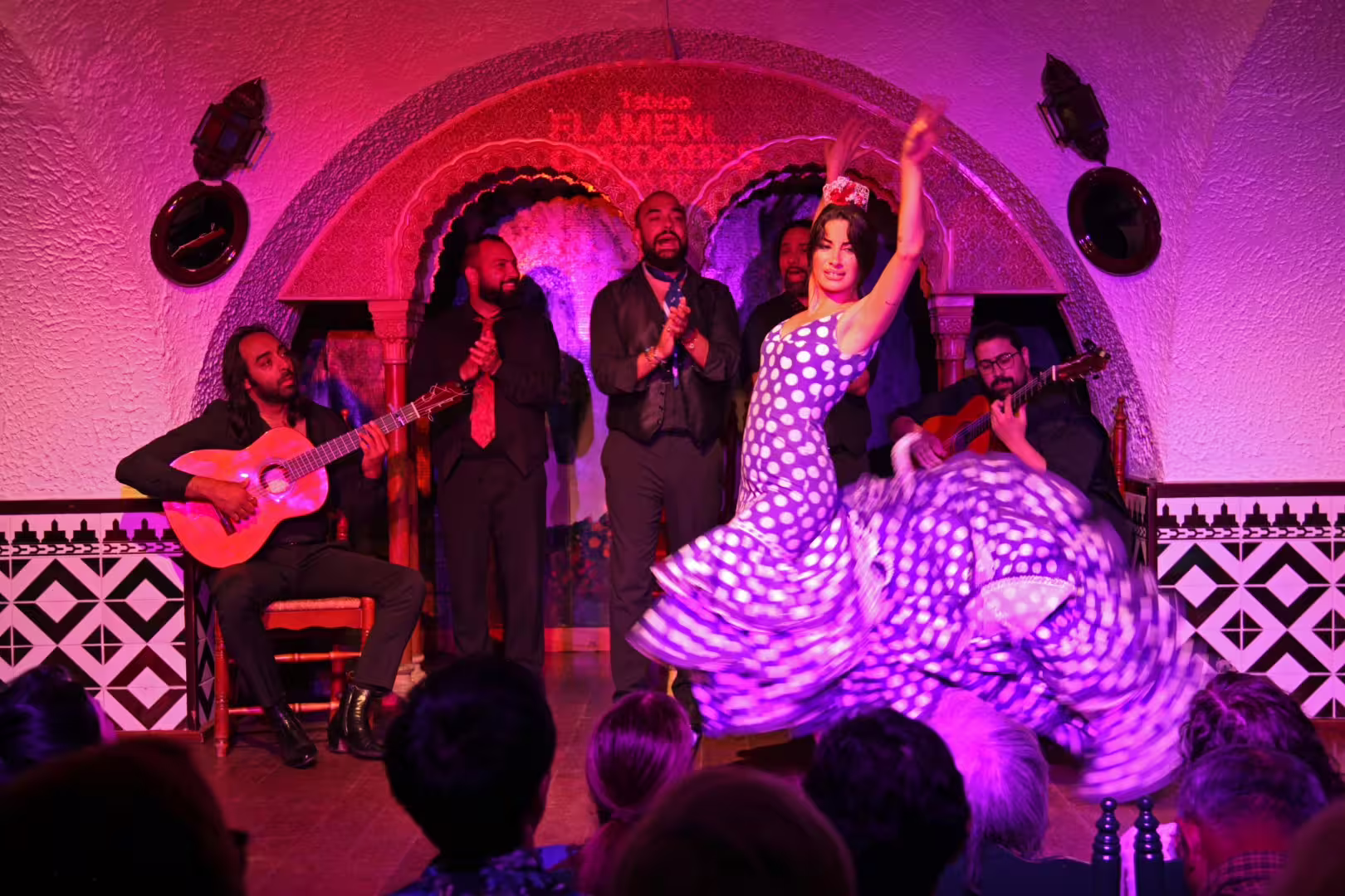 Graceful flamenco dancer in a polka dot dress captivates audience at Tablao Cordobes, Barcelona.
