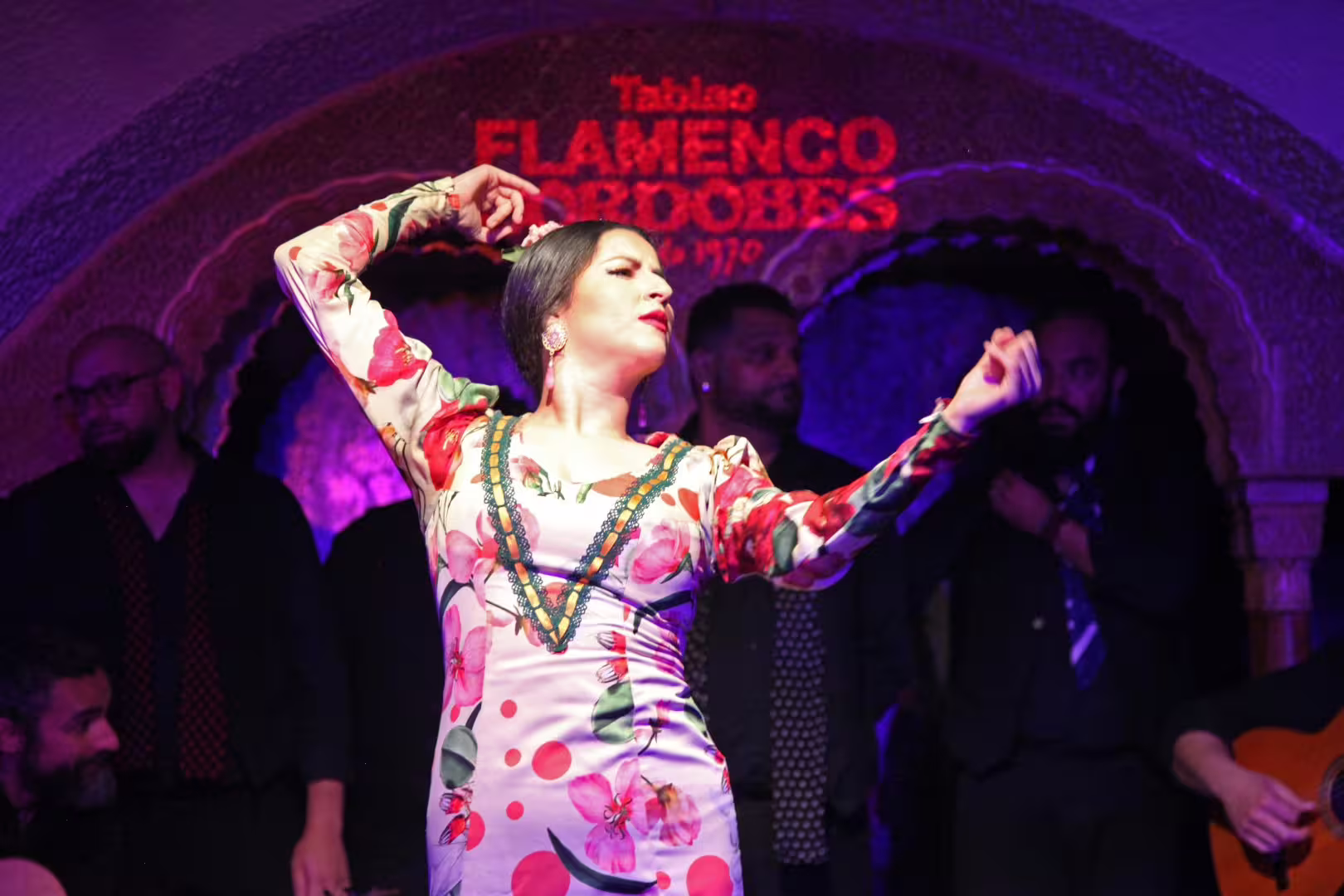 Flamenco dancer performing at Tablao Cordobes in La Rambla, Barcelona, surrounded by musicians under vibrant lighting.