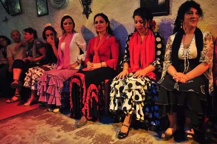 Flamenco dancers in vibrant dresses seated in a cozy Barcelona venue, highlighting a tapas, wine, and flamenco tour experience.