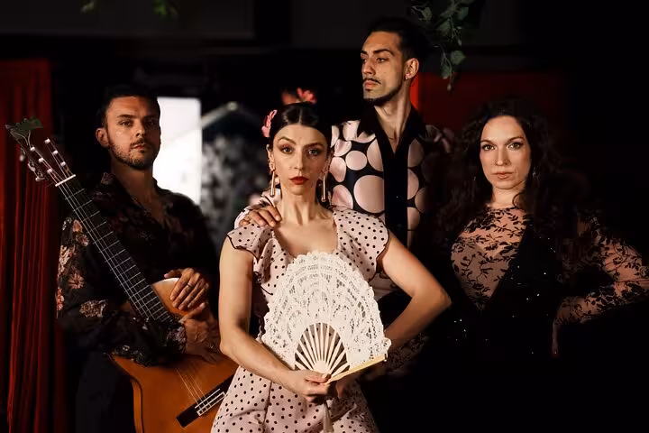 Group of flamenco performers in traditional attire with a guitar, offering an authentic cultural experience in Barcelona.
