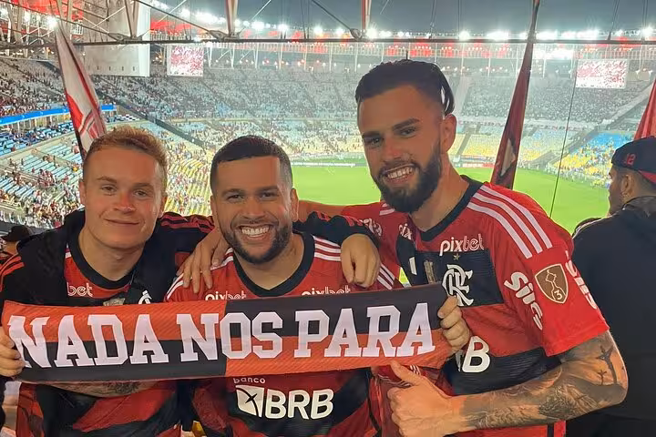 Flamengo fans holding 'Nada Nos Para' scarf with Maracanã Stadium pitch behind, Rio matchday tour experience