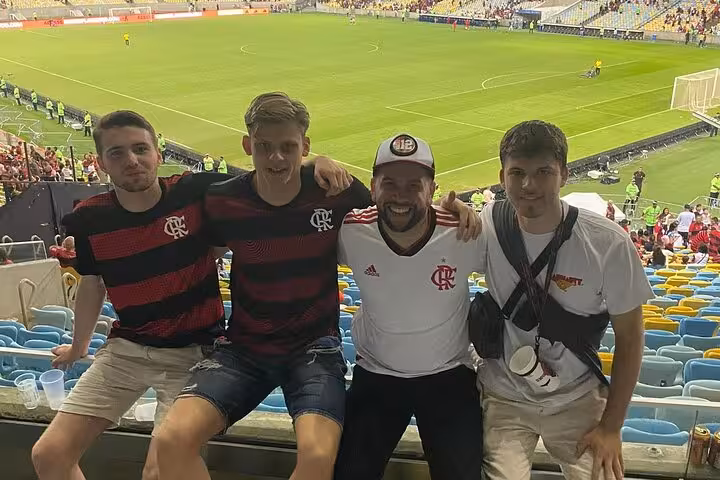 Friends in Flamengo jerseys pose in Maracanã stands with pitch view during Flamengo matchday tour in Rio