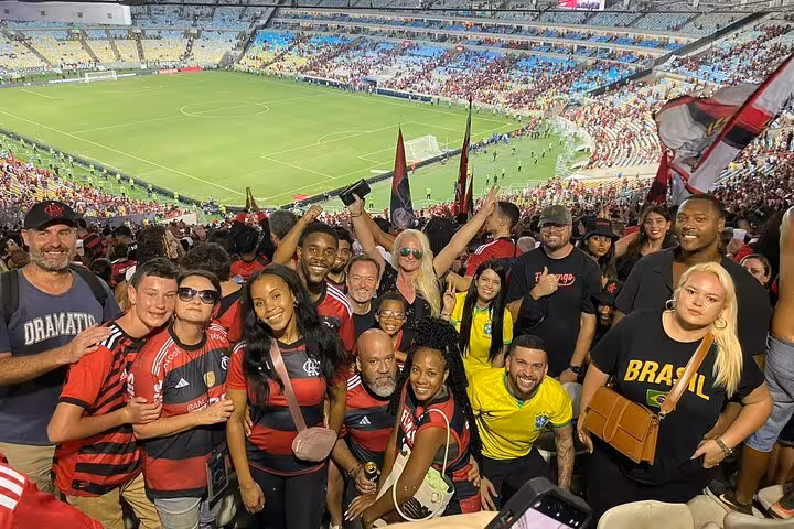 Group of Flamengo supporters posing in the stands at Maracanã Stadium with pitch view on matchday in Rio de Janeiro