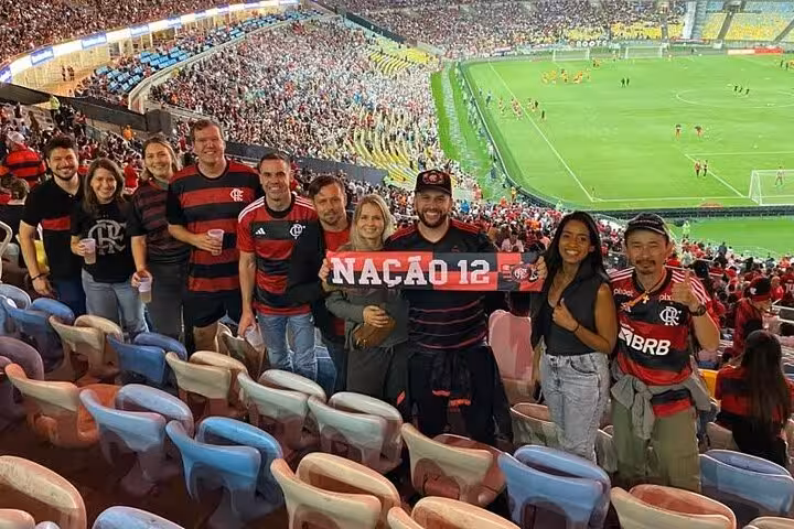 Flamengo supporters posing with 'Nação 12' scarf in Maracanã stands, Rio de Janeiro, during a live game tour