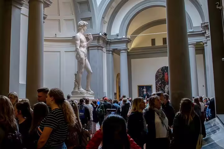Crowds on a small-group Accademia Gallery tour gathering around Michelangelo’s David statue in Florence’s famous museum hall