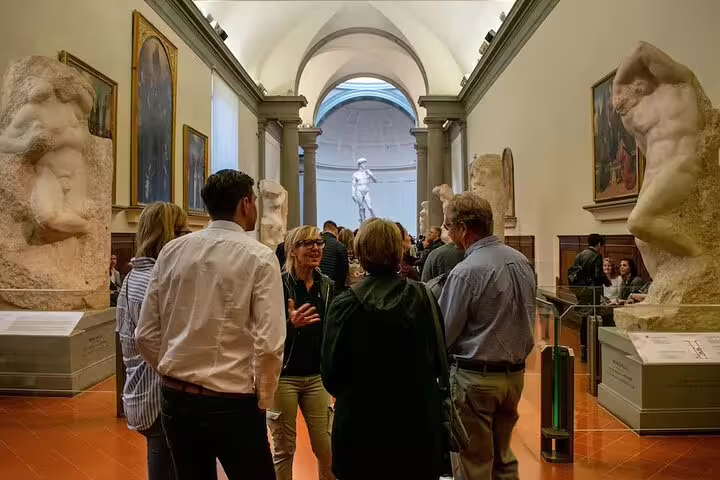 Visitors admire monumental Renaissance masterpieces in a bright Accademia Gallery hall during a small group tour with local guide