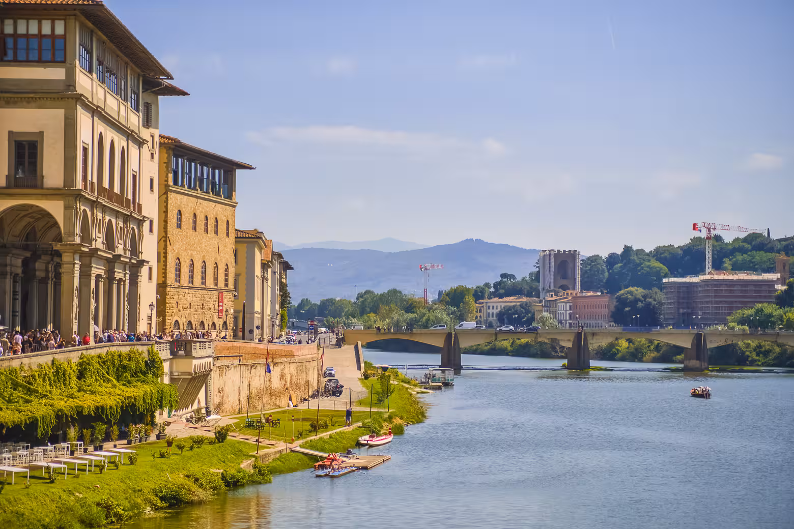 Scenic view of the Arno River and historic buildings on a sunny day in Florence, showcasing the city's charming landscape.