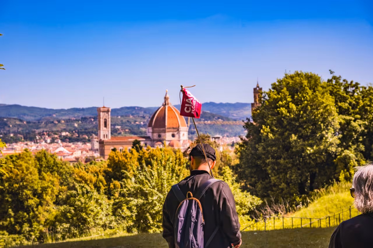 Tourist enjoying panoramic view of Florence skyline from Boboli Gardens with iconic Duomo in the background.