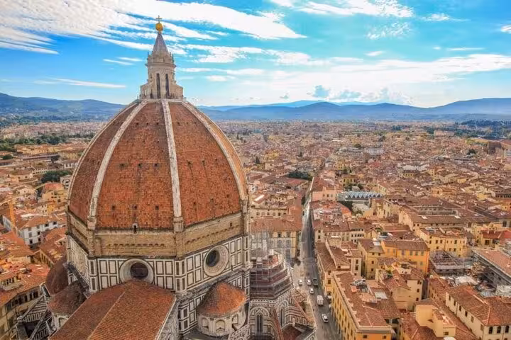 Aerial view of Florence featuring the iconic dome of the Florence Cathedral with scenic cityscape and distant hills.