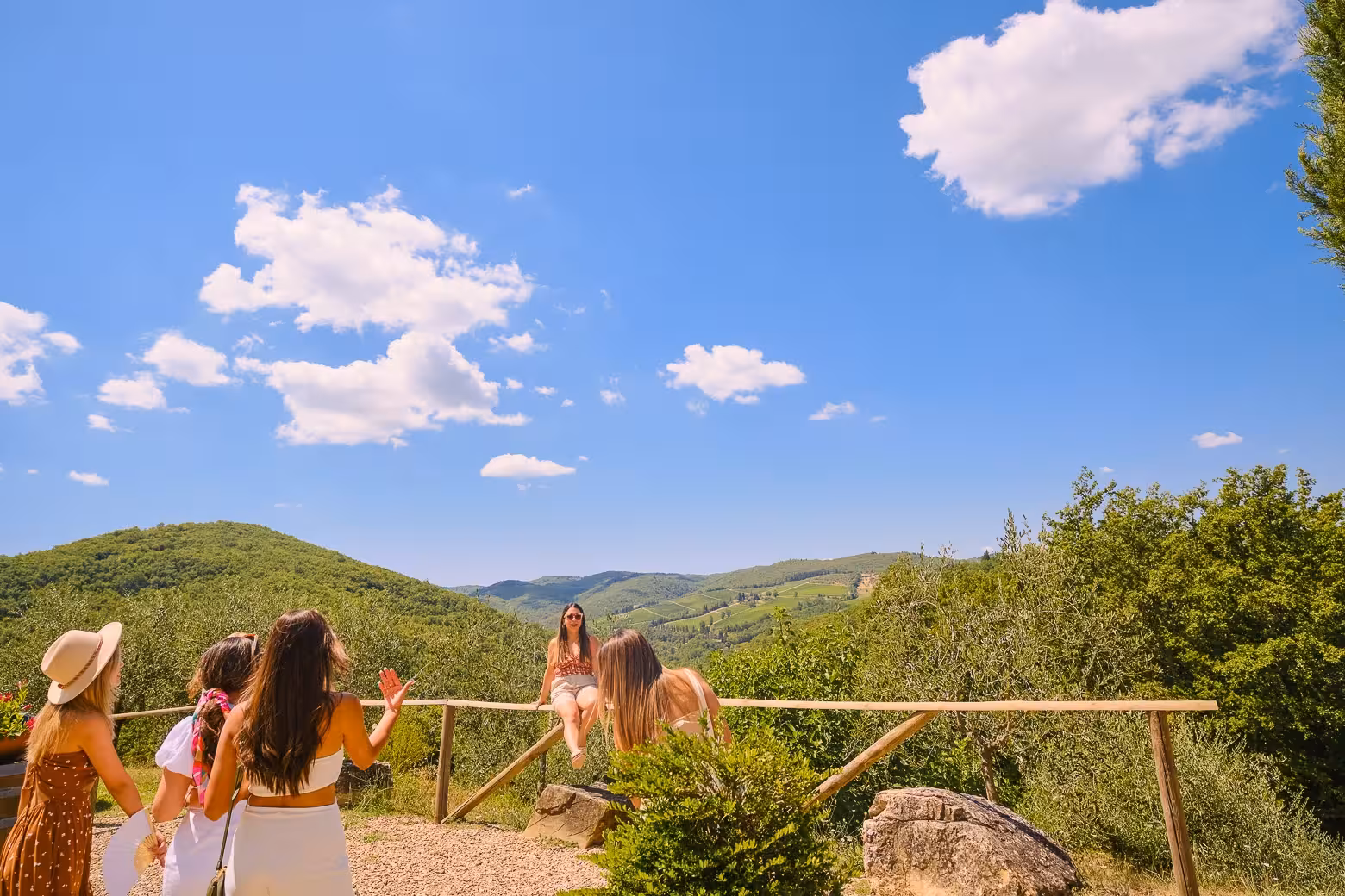 Group enjoying scenic Chianti vineyards with rolling hills and blue skies on Florence wine tour.