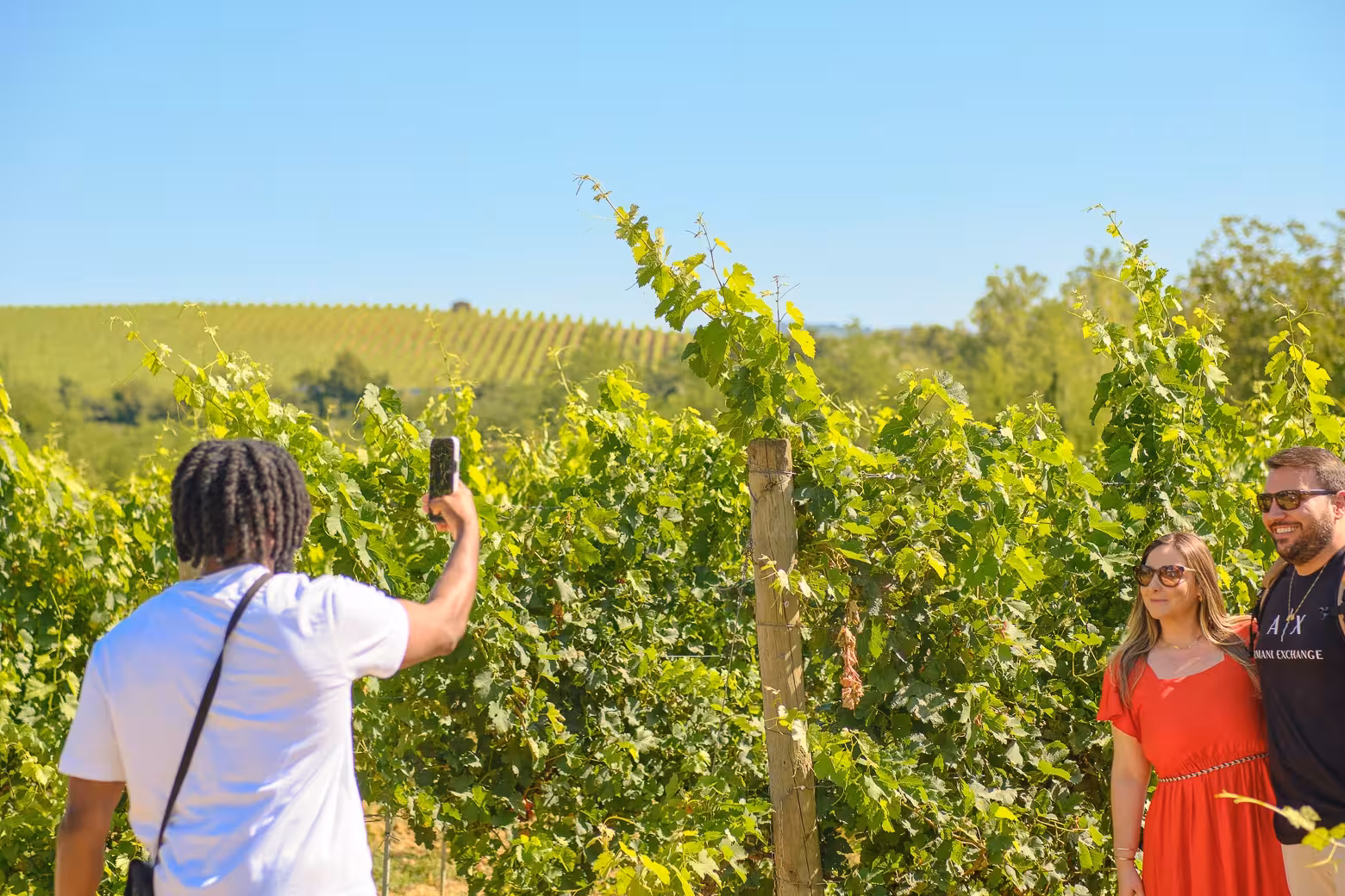 Visitors capturing photos amidst the lush vineyards of Chianti on a sunny day tour from Florence.