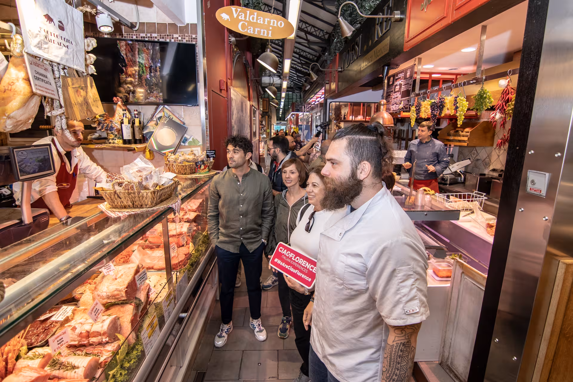 Visitors at Florence market engaged in a culinary tour, discovering premium meats and Tuscan specialties.