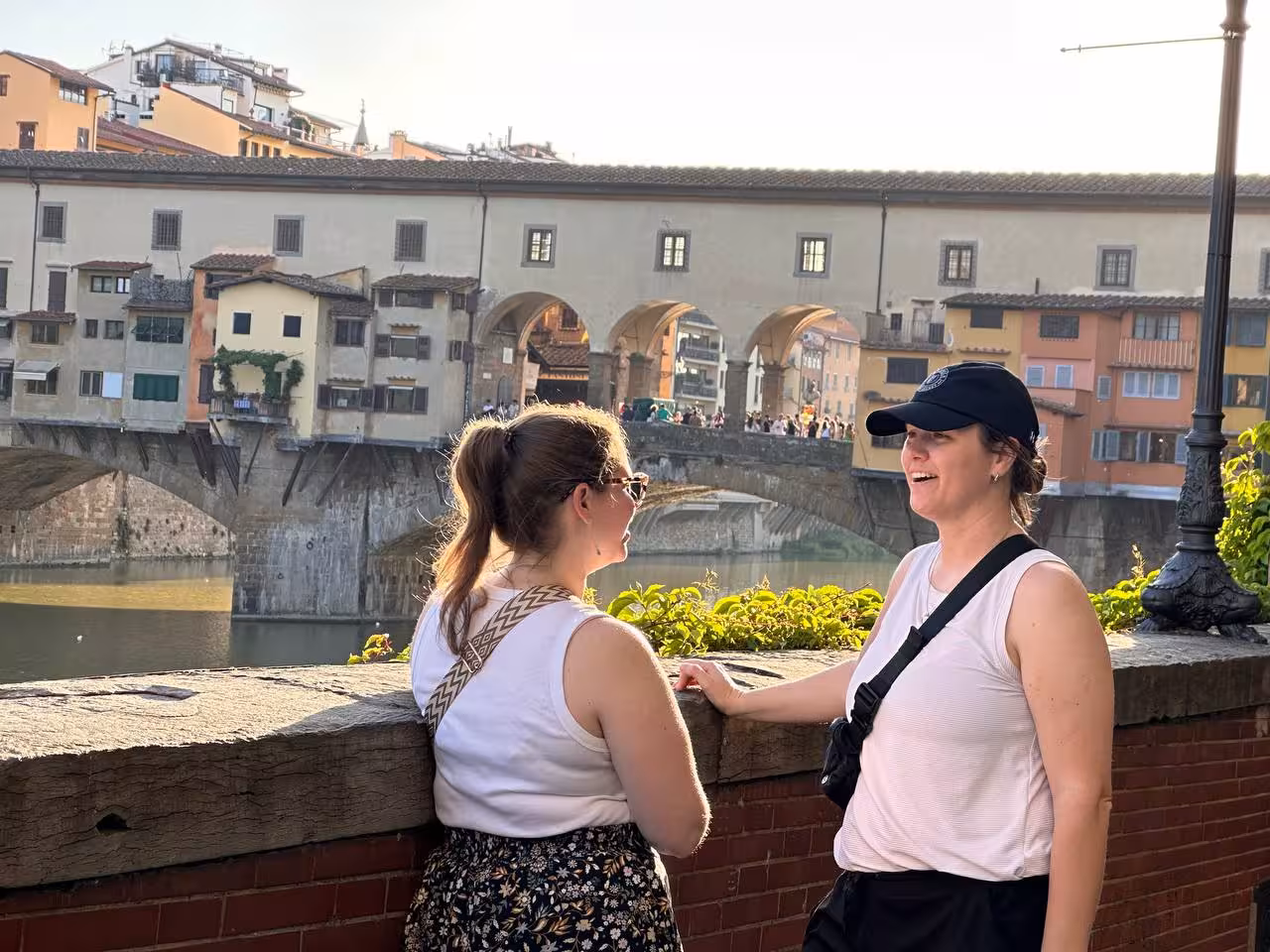 Two visitors chatting by Ponte Vecchio, capturing the essence of a Florence day tour.