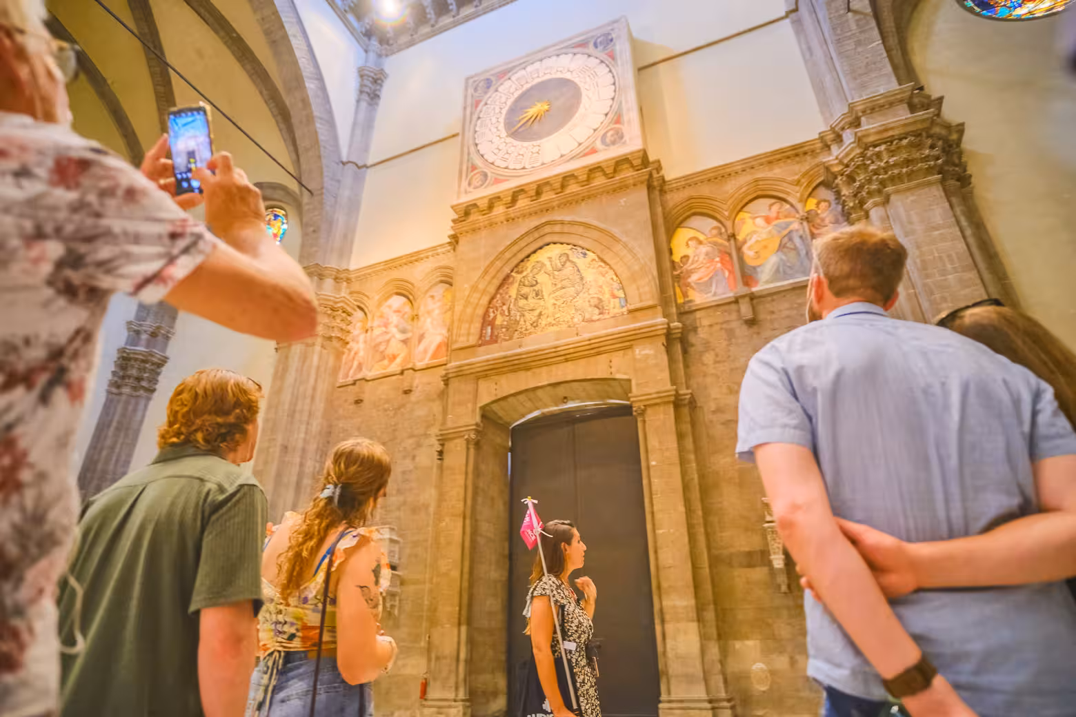 Visitors admire historic frescoes and the iconic clock inside Florence's Duomo Cathedral during a guided tour.