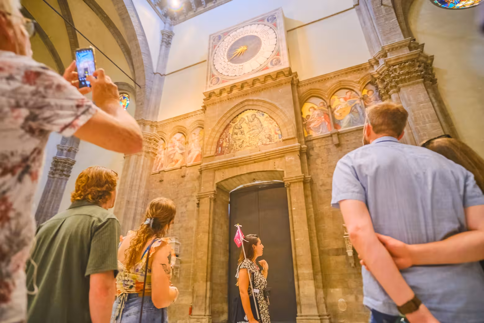 Tourists admire the intricate frescoes and clock inside Florence's Duomo Cathedral on a guided tour.