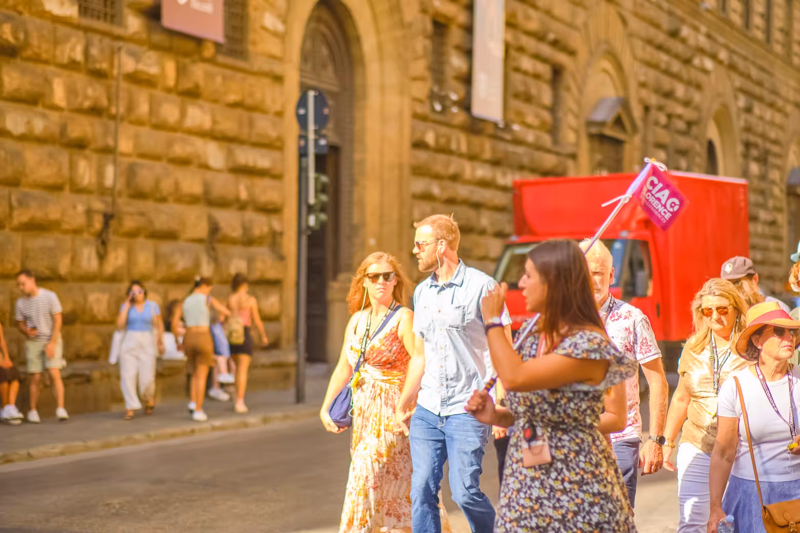 A guided tour group explores Florence's historic streets, led by a guide holding a flag near the Duomo Cathedral.