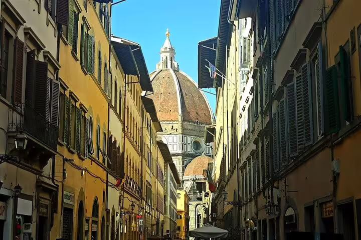 Narrow Florence street opening to the iconic Duomo cathedral dome, seen on a private day trip from Livorno with Chianti option