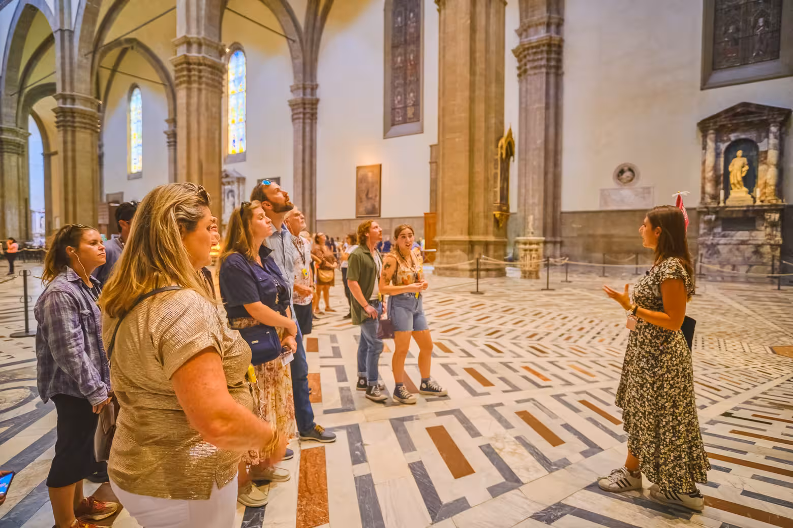 Tour group explores Florence's Duomo interior with guide explaining architectural details and history.