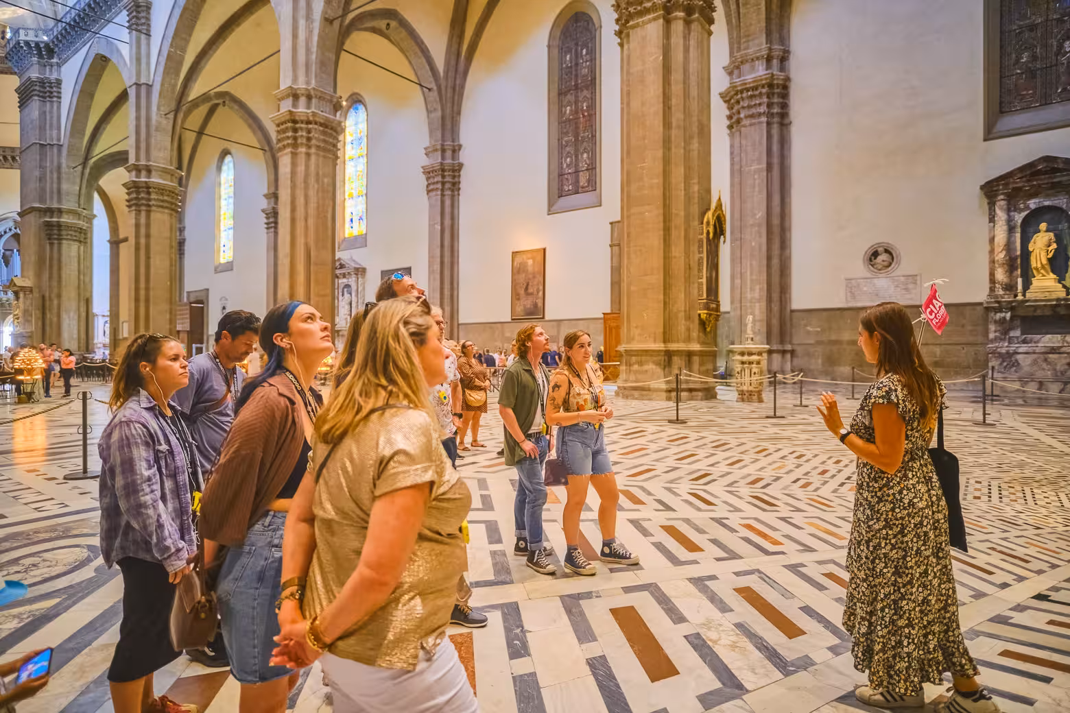 Visitors at Florence's Duomo listening intently to a guide discuss the cathedral's stunning architecture.