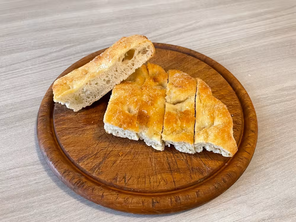 Freshly sliced focaccia bread on a wooden board, part of the surprise tasting on Florence E-bike tours.
